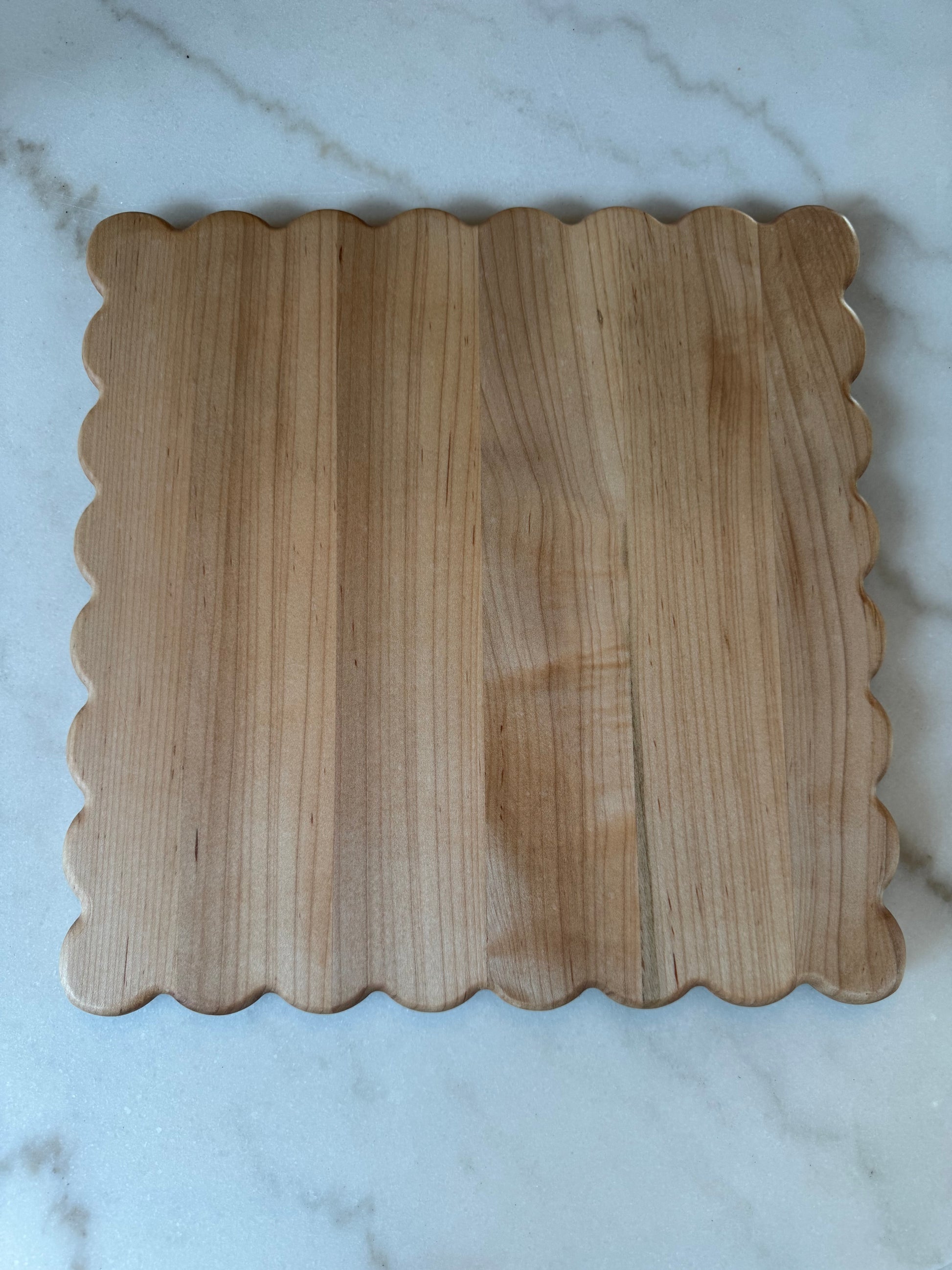 Haylee scalloped-edge cutting board made from solid maple hardwood, shown on a marble surface