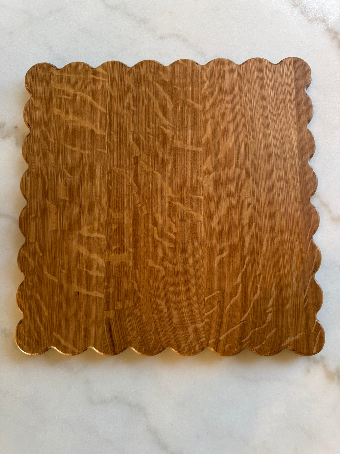 Haylee scalloped-edge cutting board made from quarter-sawn white oak, shown on a marble surface