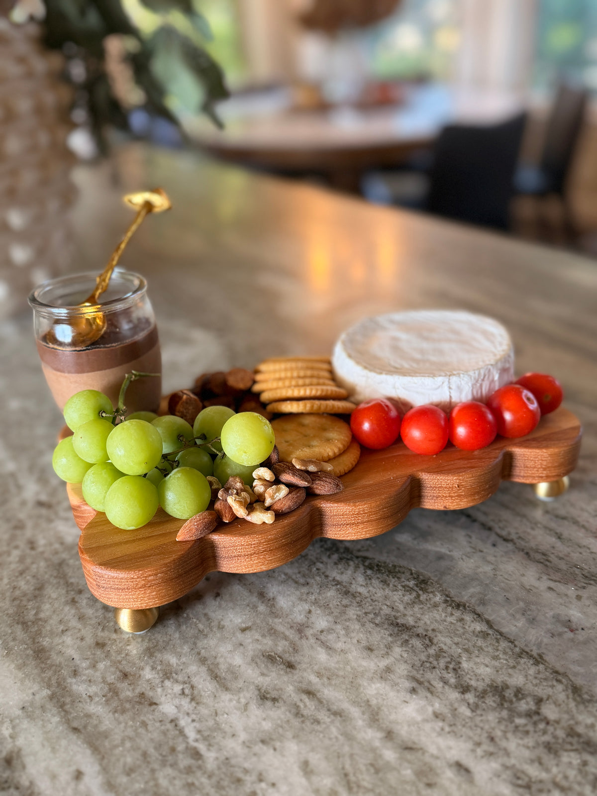 The Dixie scalloped board on brass feet styled with grapes, tomatoes, crackers, brie, nuts and honey