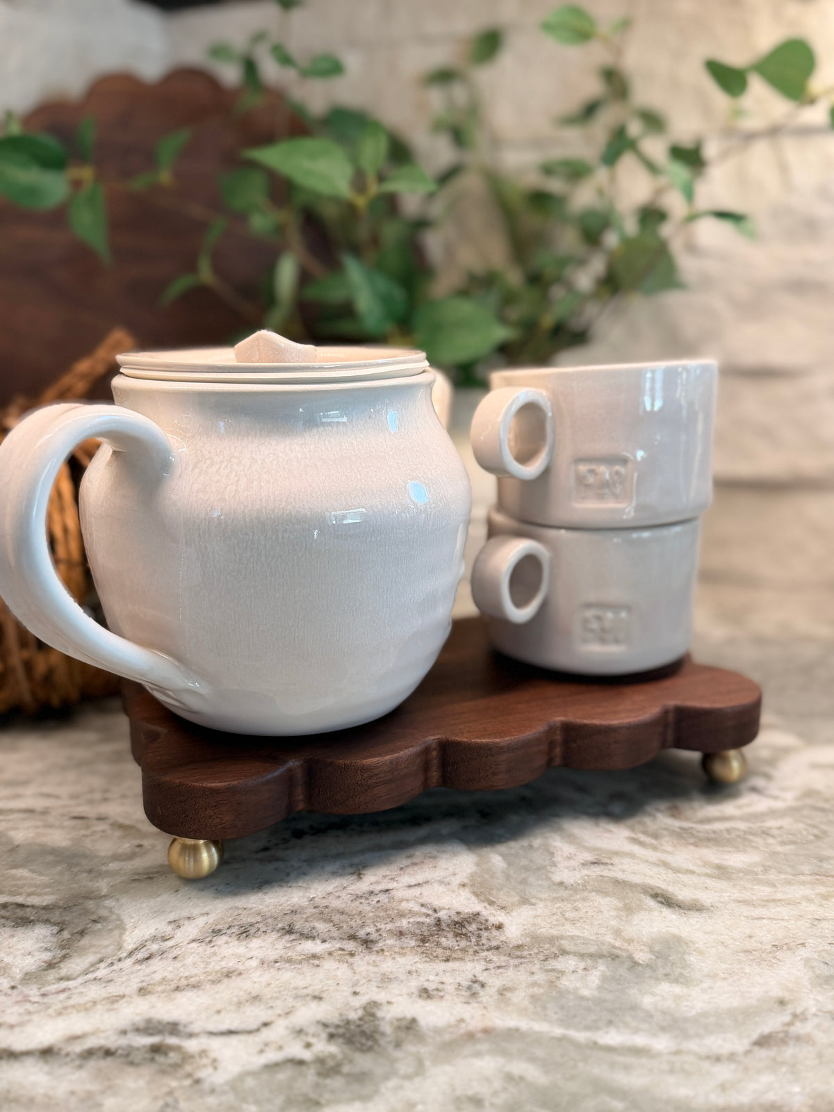 The Dixie dark wood scalloped board on brass feet holding a white teapot and mugs